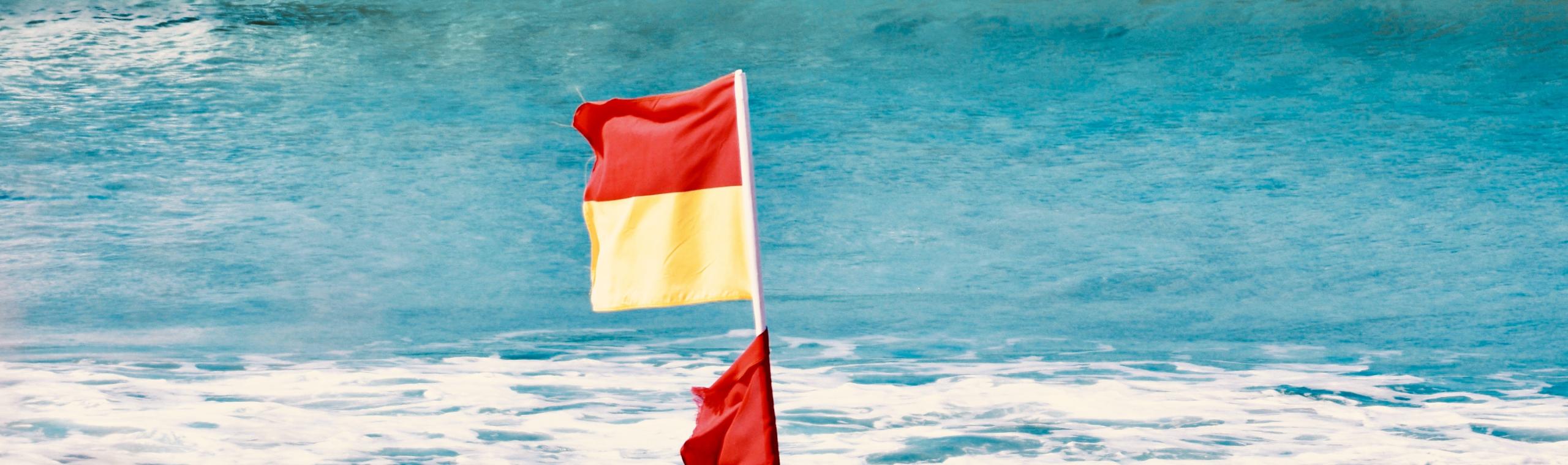 Waarschuwingsvlag rood en geel op het strand