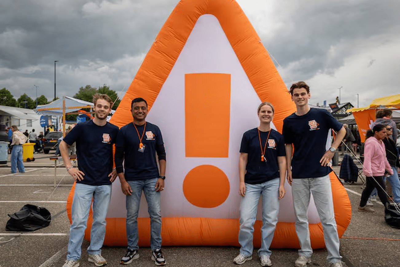 Een foto van een grote opblaasbare gevarendriehoek met mensen op de voorgrond