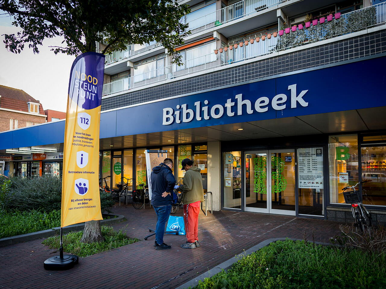Foto van twee mannen in gesprek met elkaar voor de bibliotheek